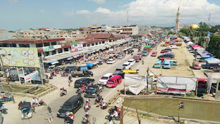 WhatsApp Image 2026-09-21 at 101945 - Mabur.co A crowded outdoor market stalls line a street, with tents, cars, and pedestrians seen from an elevated vantage point