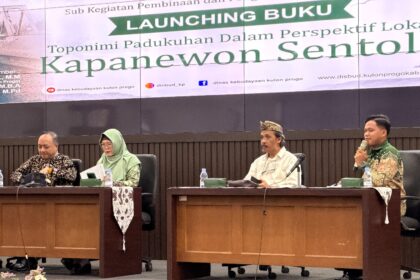 Four panelists sit at a conference table on a stage, microphones in front, with a large 'LAUNCHING BUKU' banner in the background.