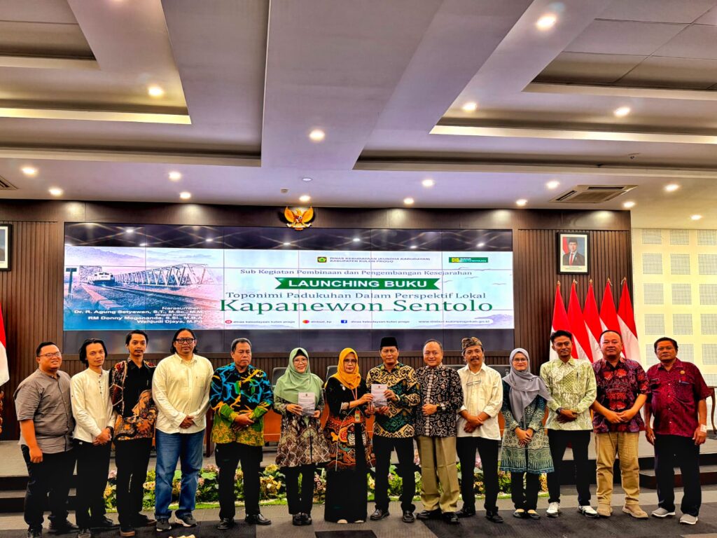 WhatsApp Image 2026-10-20 at 204215 - Mabur.co Group of people posing on stage at a book launch event, with a banner reading 'Launching Buku' in the background and Indonesian flags nearby.