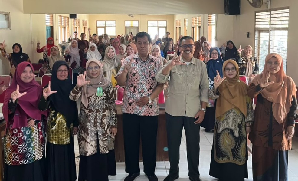 WhatsApp Image 2026-10-21 at 130135 - Mabur.co Group of adults posing for a group photo in a classroom, front row wearing batik and hijabs.