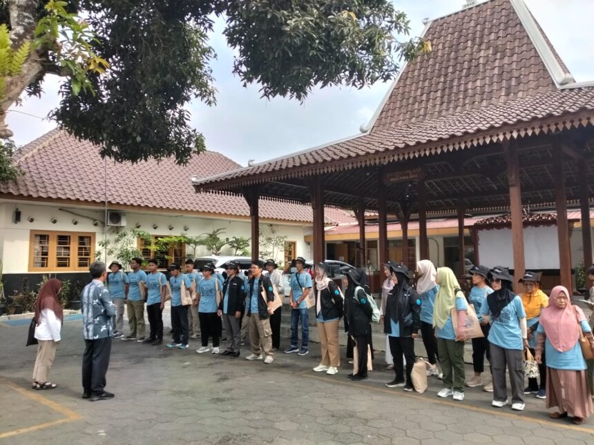 Group of people in blue shirts lined up in an outdoor courtyard, listening to an instructor at the front.