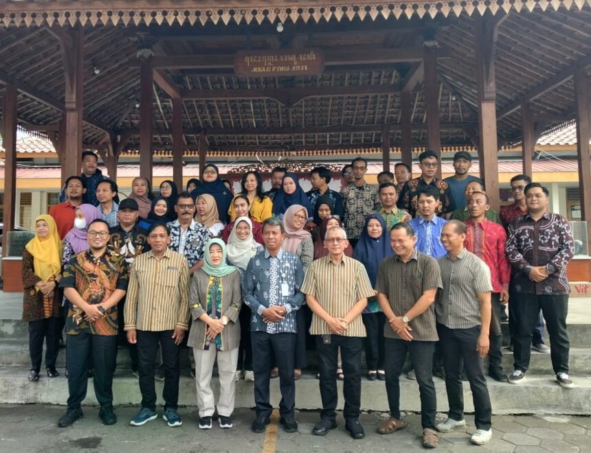 Large group of men and women posing for a group photo under a wooden pavilion outdoors.