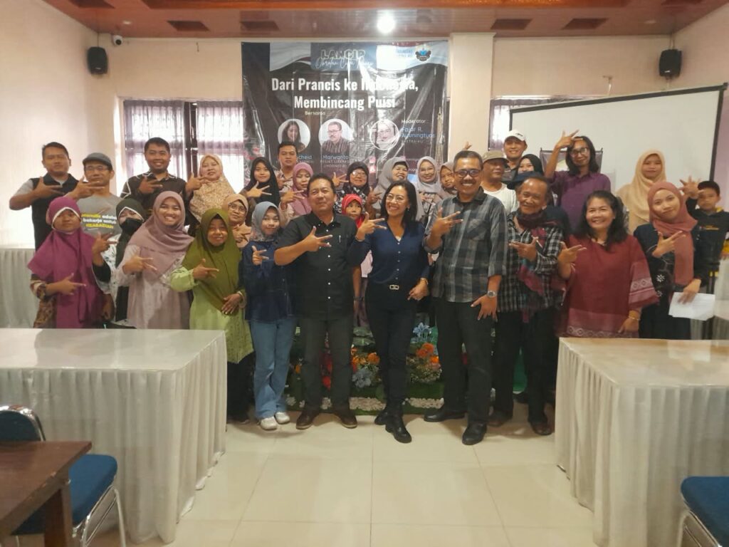 WhatsApp Image 2026-10-25 at 1356161 - Mabur.co Large group of men and women posing for a group photo at an indoor event, with a banner and projection screen in the background.