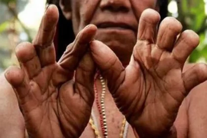 Close-up of dark-skinned hands forming a circle with thumbs and index fingers, beads visible in the background