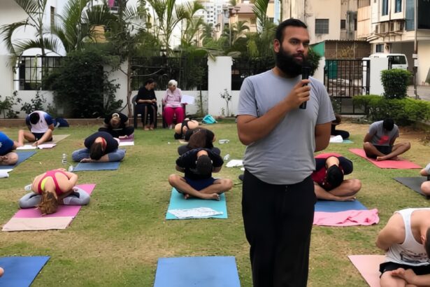 Instructor with microphone speaks to a group doing yoga outdoors on mats in a garden courtyard.