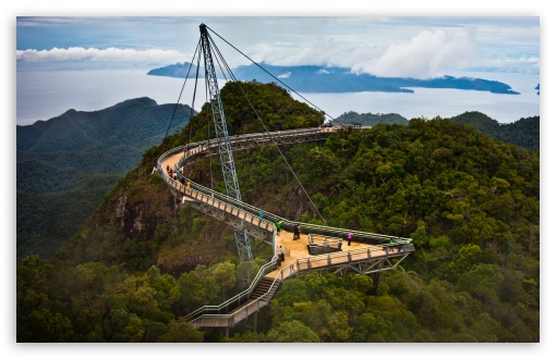aAZA - Mabur.co Suspension skywalk extending over a forested canyon with distant blue sea.