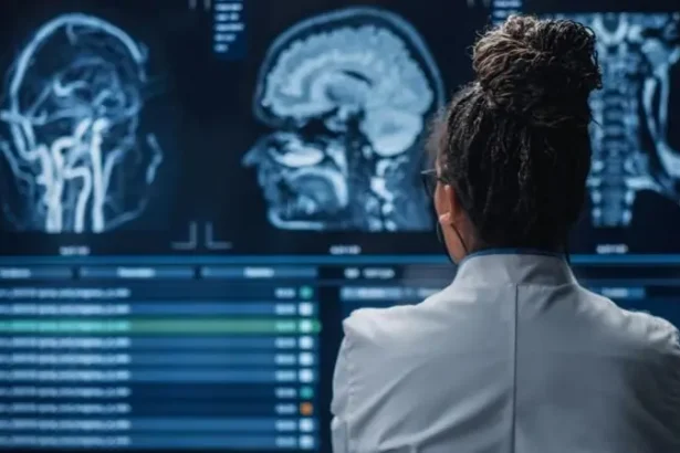 Medical professional in a white coat analyzes MRI brain scans projected on multiple screens.