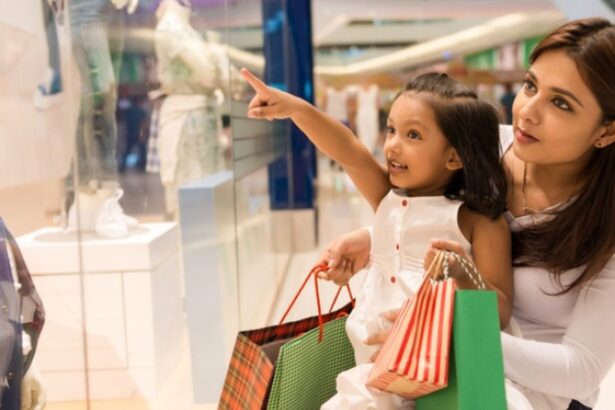 Mother and young girl shopping in a mall, the child pointing at a store window display while carrying gift bags.