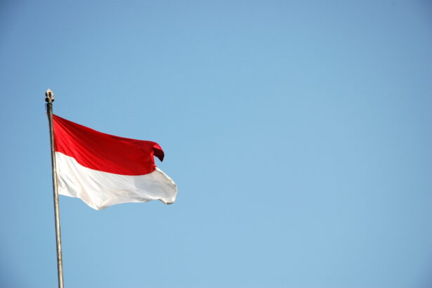 Indonesian flag waving from a flagpole against a clear blue sky.