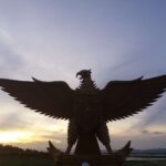 Silhouette of a large eagle statue with outstretched wings at sunset.