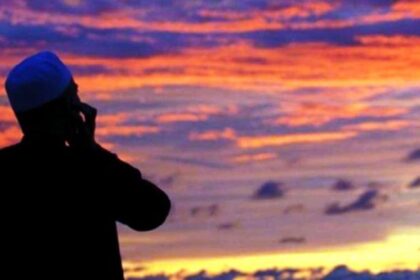 Silhouette of a man talking on a mobile phone against a vibrant sunset sky with orange and purple clouds.