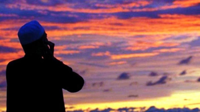 Silhouette of a man talking on a mobile phone against a vibrant sunset sky with orange and purple clouds.