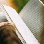Close-up of hands holding and turning the pages of an open book, bathed in warm natural light