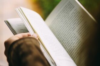 Close-up of hands holding and turning the pages of an open book, bathed in warm natural light