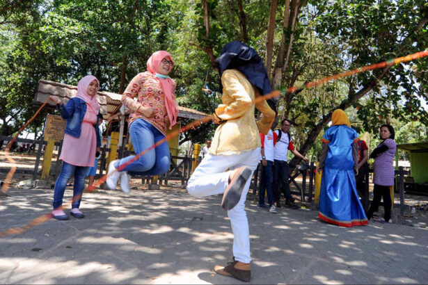 Group of women and girls skipping rope in a sunny park surrounded by trees.