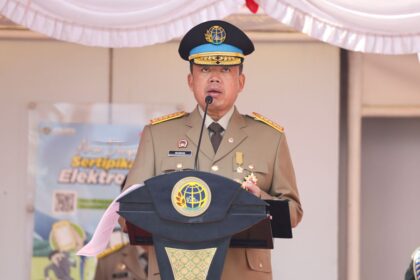 Uniformed official delivering a speech at a podium with a globe emblem and medals on his chest.