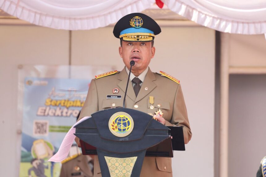 Uniformed official delivering a speech at a podium with a globe emblem and medals on his chest.
