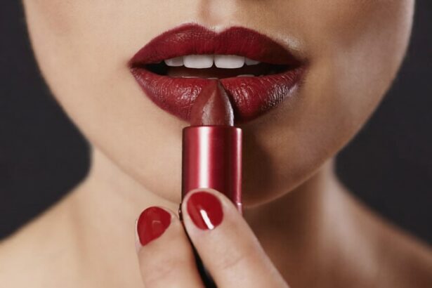 Close-up of a person applying red lipstick from a metallic tube.
