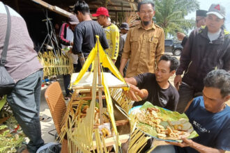 Group of men around an outdoor street food stall, serving fried snacks displayed on banana leaves.