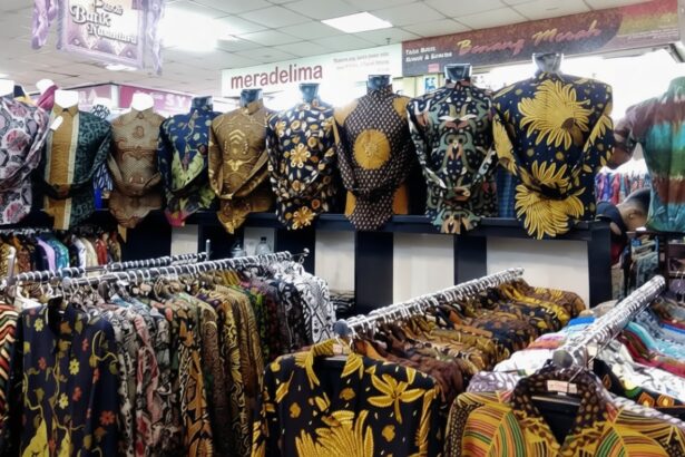 Rows of colorful batik shirts on hangers and mannequins in a busy clothing store nearby racks of patterned shirts in a textile shop.