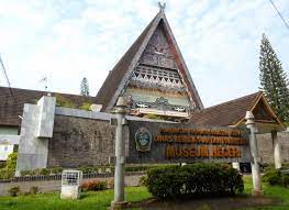 download-2021-09-01T020256282 - Mabur.co Front view of a state museum entrance with a sign and a traditional gable-roof building in the background