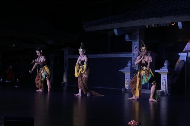 Three dancers in gold-brown traditional costumes perform on a dimly lit stage.