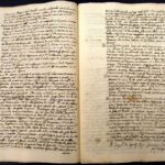 Open two-page spread of an antique manuscript with dense cursive handwriting and yellowed, stained pages on a dark background.