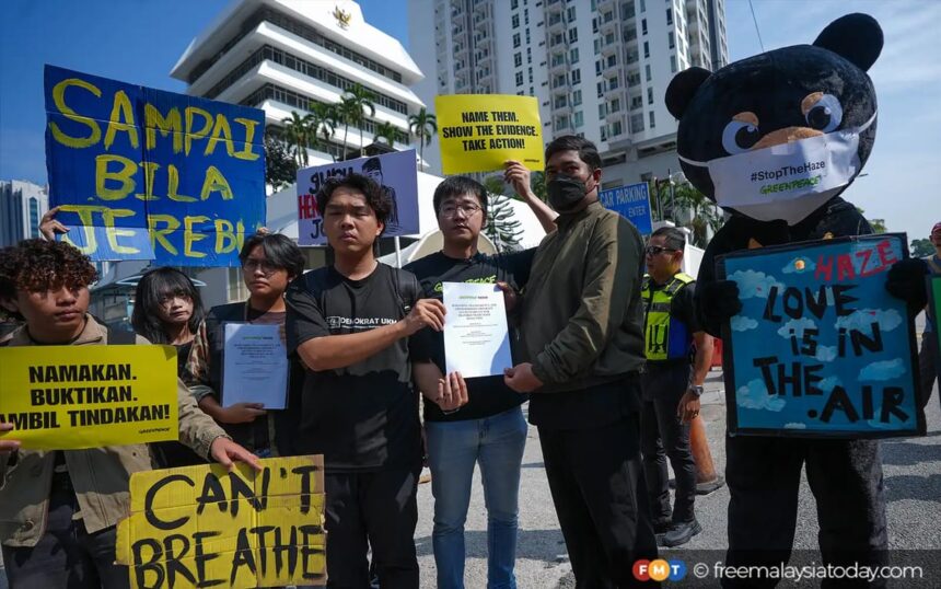 Group of protesters holding bright yellow placards; two men exchange a document while a panda mascot stands on the right with a sign about haze