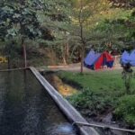 Campsite along a pond with colorful tents and trees; a wooden sign reads 'I ❤️ GROGOL' in the background.
