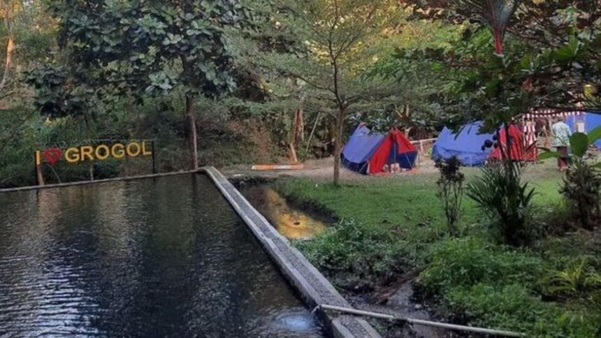 Campsite along a pond with colorful tents and trees; a wooden sign reads 'I ❤️ GROGOL' in the background.