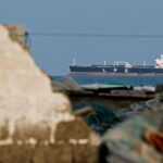 Large LPG tanker on the sea, viewed through foreground rubble and debris.