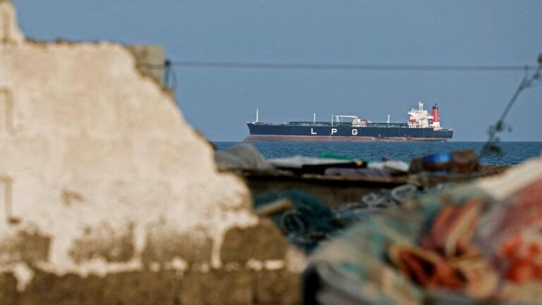 Large LPG tanker on the sea, viewed through foreground rubble and debris.