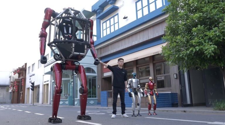 Man in a black shirt stands beside a towering red mechanical robot on a city street, with two smaller robots nearby.