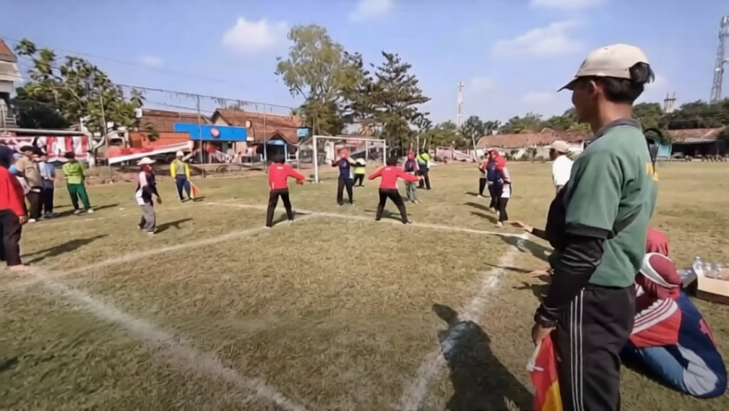 gobak sodor by kompas tv YT-ezremove-ezremove - Mabur.co Group of people playing a field game on a grassy sports ground, with spectators and small goals in the background on a sunny day.
