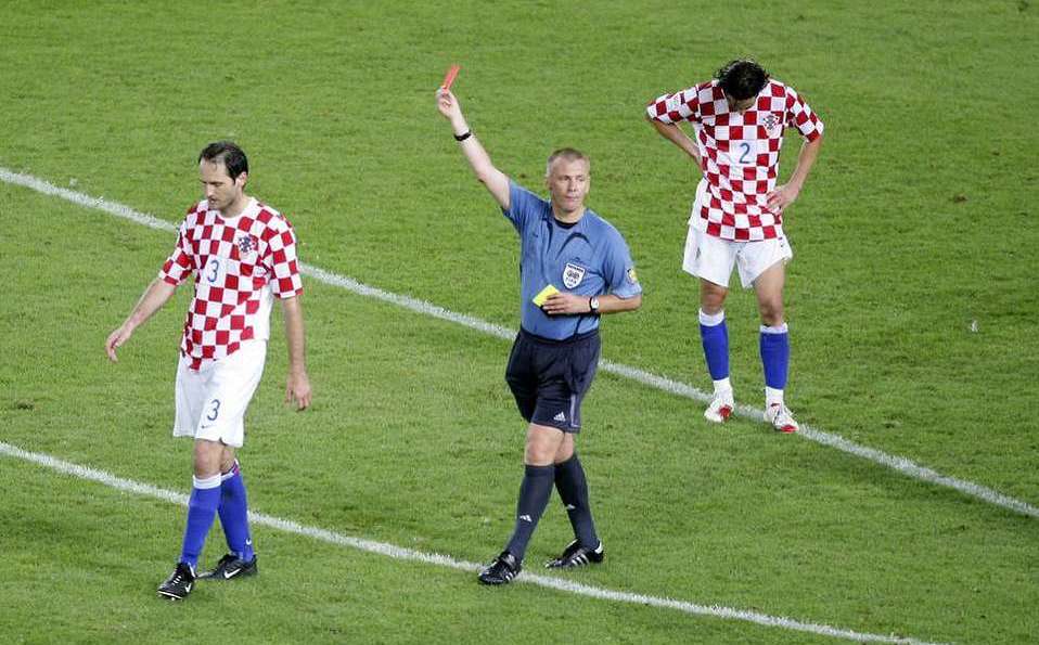 graham poll 3 yellow cards josip simunic by mediotiempo - Mabur.co Soccer referee in blue raises a yellow card while two players in red-and-white checkered jerseys look on on a green pitch in formation.