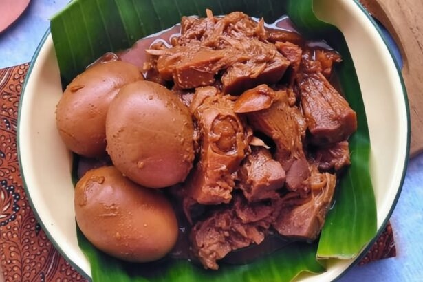 Plate with braised meat and three hard-boiled eggs on a banana leaf liner.