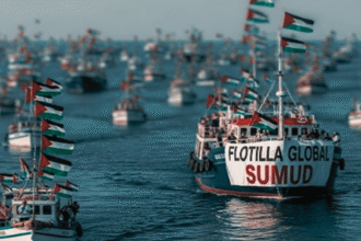 A flotilla of boats at sea with Palestinian flags; the lead boat's banner reads 'FLOTILLA GLOBAL SUMUD'.