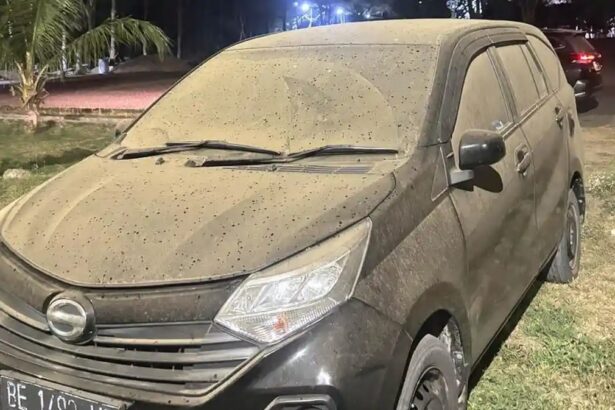 Dusty dark SUV parked on grass at night, with mud splatters coating the body and windshield wipers resting on the windshield