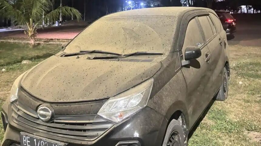 Dusty dark SUV parked on grass at night, with mud splatters coating the body and windshield wipers resting on the windshield