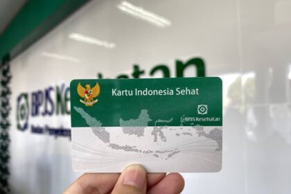 Indonesian health card Kartu Indonesia Sehat (BPJS Kesehatan) held up in front of a blurred backdrop