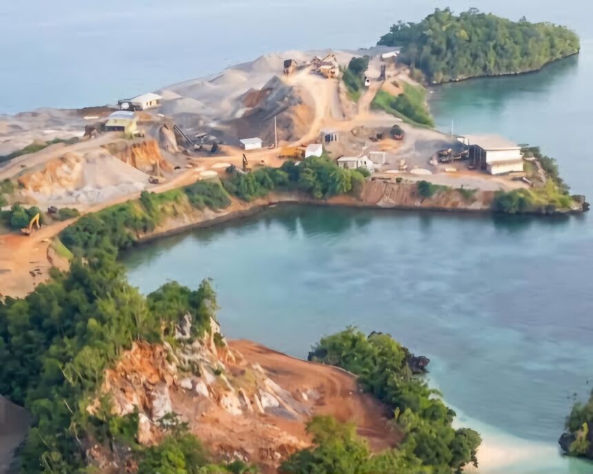 images 1 - Mabur.co Aerial view of a small rocky island with exposed dirt and excavation equipment along winding paths, surrounded by calm blue water.