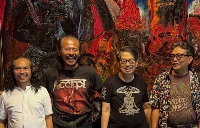 images - Mabur.co Four men stand side by side, smiling, in front of a vibrant abstract wall of red and black textures.