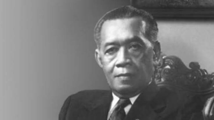 Black-and-white formal portrait of a middle-aged man in a suit seated in a chair with a neutral expression.