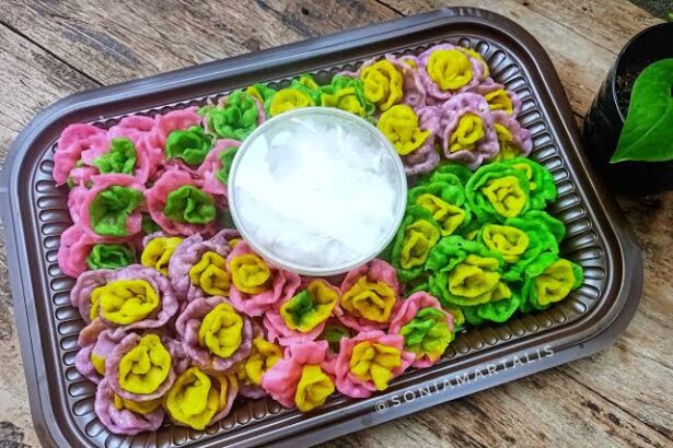 Colorful flower-shaped dumplings in pink, purple, yellow, and green arranged on a brown tray with a bowl of ice in the center.