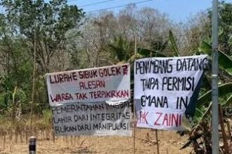 Two handwritten protest banners beside a road, criticizing local officials' integrity and permit handling, in a dry rural area.
