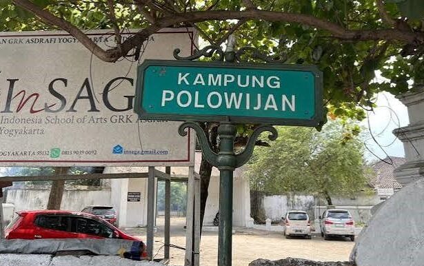Green street sign reading 'KAMPUNG POLOWIJIAN' on a decorative post, with a banner and parked cars behind.