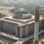 Large government complex under construction with a domed central structure and columned wings.