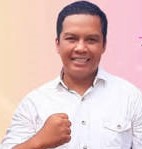 Smiling man in a white shirt raises his fist in a confident pose against a pink gradient backdrop.