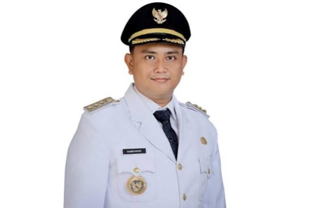 Portrait of a man in a white ceremonial uniform and peaked cap, facing the camera with a neutral expression.