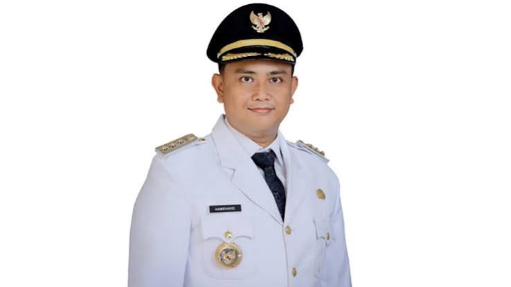 Portrait of a man in a white ceremonial uniform and peaked cap, facing the camera with a neutral expression.